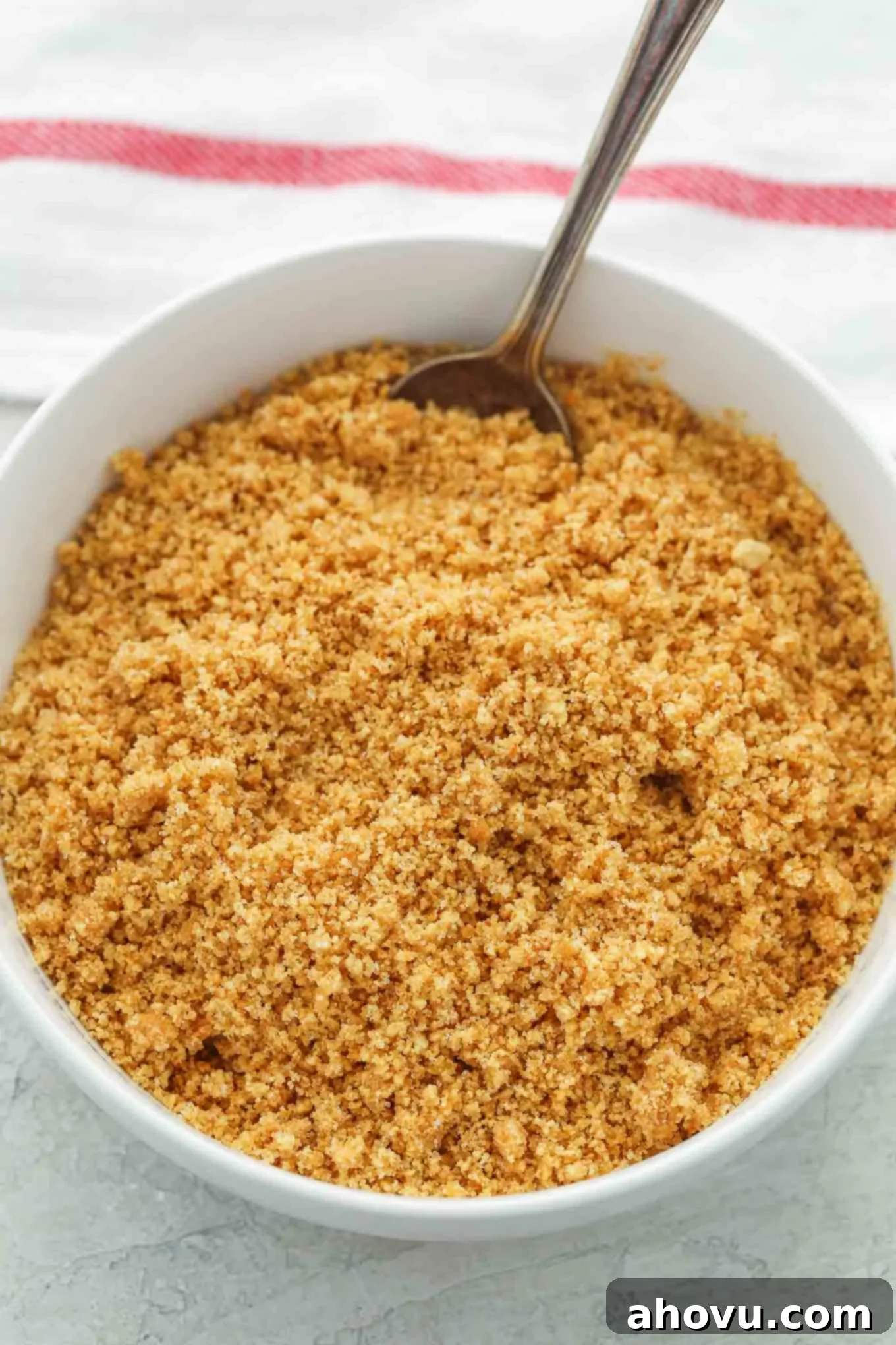 Lemon Blueberry Cheesecake Bites 5 Overhead view of graham crackers crumbs in a white bowl with a spoon sticking out.