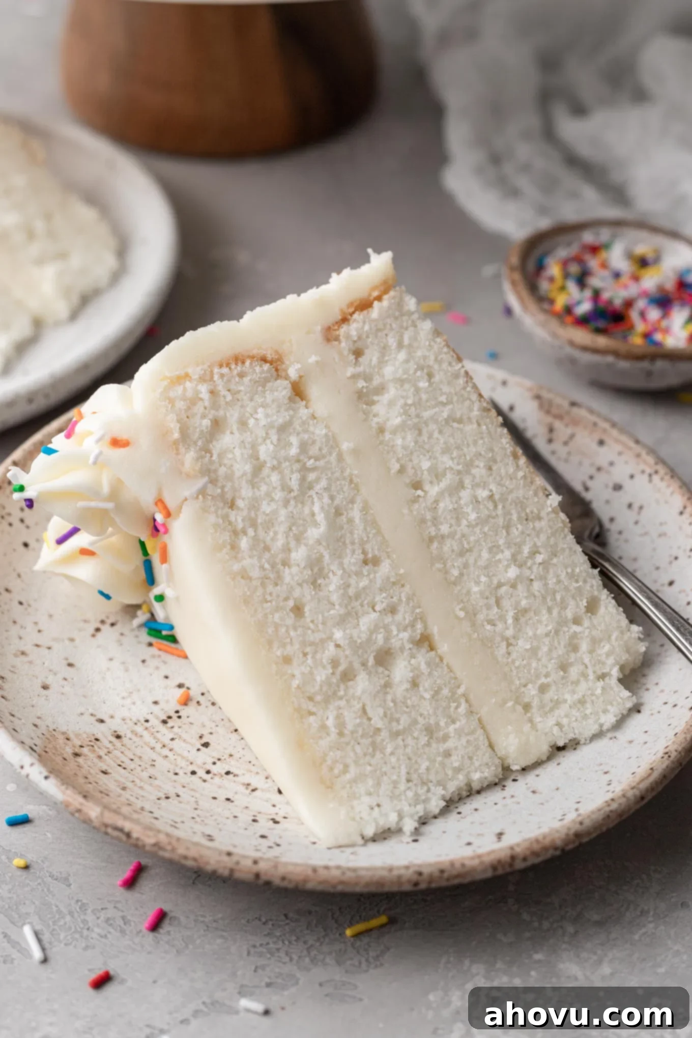 A slice of white cake on a dessert plate. 