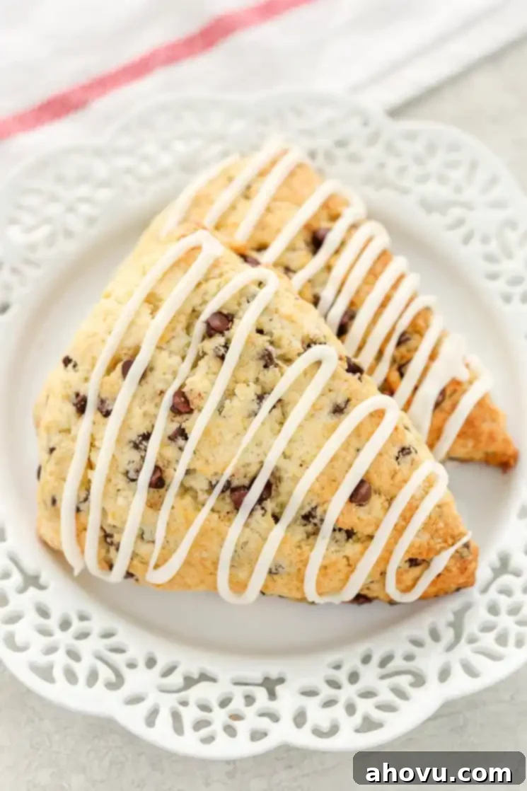 Irresistible Chocolate Chip Scones 2 Two glazed chocolate chip scones on a white plate.