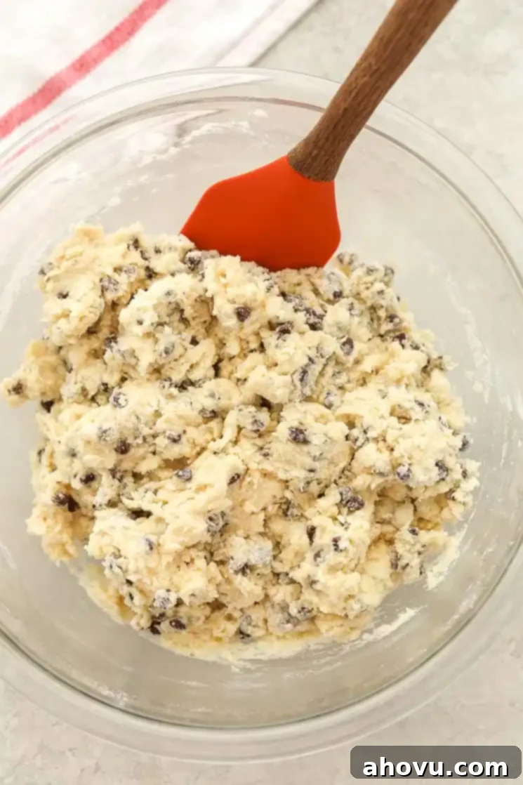 Irresistible Chocolate Chip Scones 3 Homemade chocolate chip scone batter in a glass mixing bowl with a spatula.
