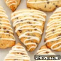 Irresistible Chocolate Chip Scones 6 Several iced chocolate chip scones sitting on top of a piece of parchment paper.