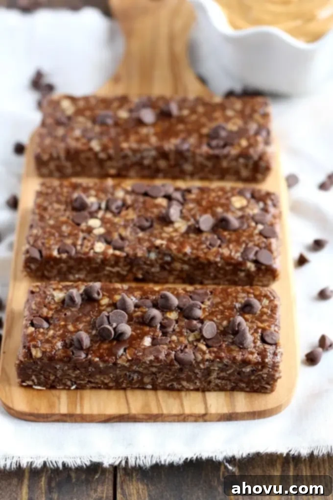 Effortless No-Bake Chocolate Peanut Butter Granola Bars 3 Three homemade chewy chocolate chip granola bars on a wood board.