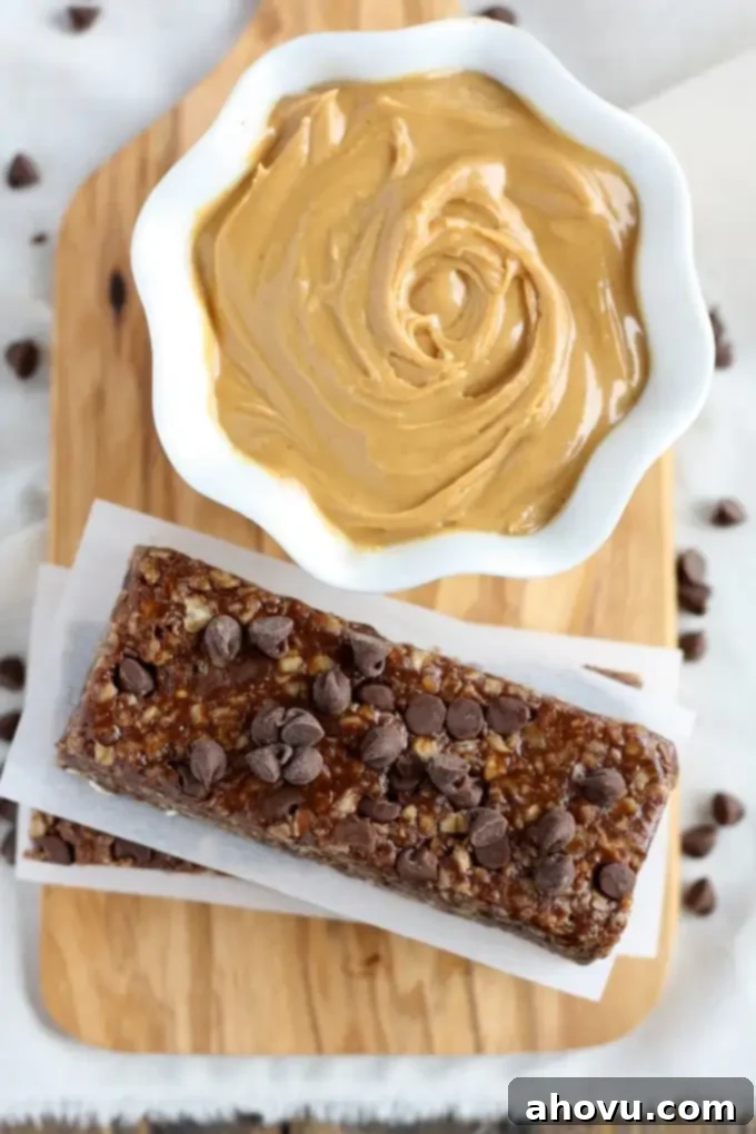 Effortless No-Bake Chocolate Peanut Butter Granola Bars 4 Overhead view of a stack of healthy peanut butter chocolate chip granola bars and a bowl of peanut butter on a wood board.
