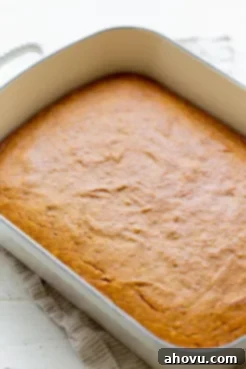 A golden-brown pumpkin cake baked in a 9 by 13 inch pan, cooling and ready for frosting.