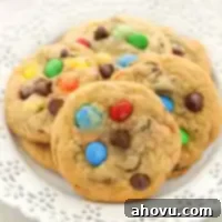 Several M&M's cookies on a decorative white plate.