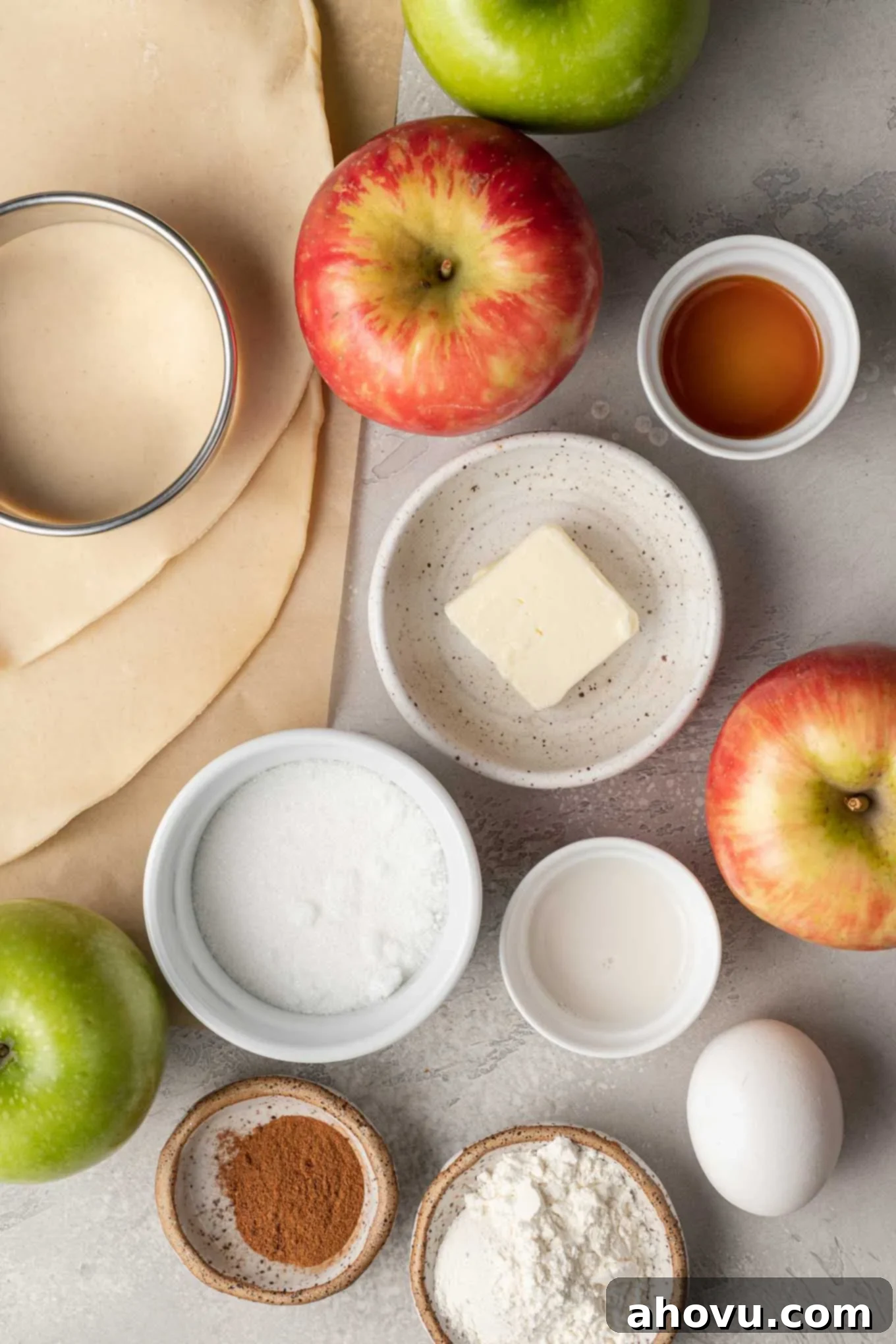 Flaky Apple Turnovers 3 An overhead view of all the fresh and dry ingredients meticulously laid out on a clean surface, ready for making hand held apple pies, including apples, flour, sugar, and spices.