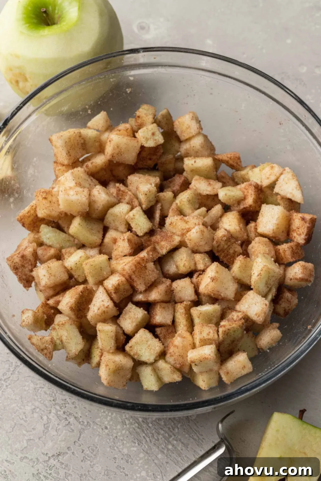 Flaky Apple Turnovers 4 A clear glass mixing bowl filled with freshly prepared apple pie filling, showing diced apples coated in sugar and spices, ready for assembly.