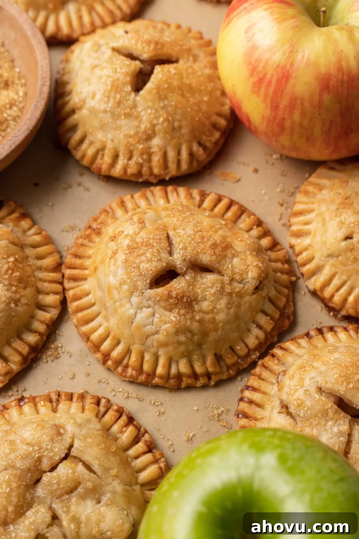 Flaky Apple Turnovers 8 A baking sheet lined with parchment paper, holding several freshly baked, golden-brown apple hand pies, steam visibly escaping from their tops.