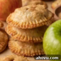 Flaky Apple Turnovers 10 Three golden-brown apple hand pies stacked neatly on top of each other, showcasing their flaky crust and inviting texture.