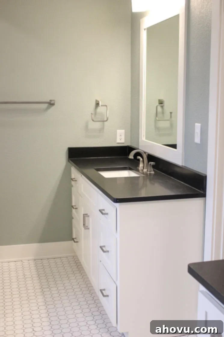 A pristine bathroom featuring white subway tiles, elegant white cabinetry, and contrasting black granite countertops.