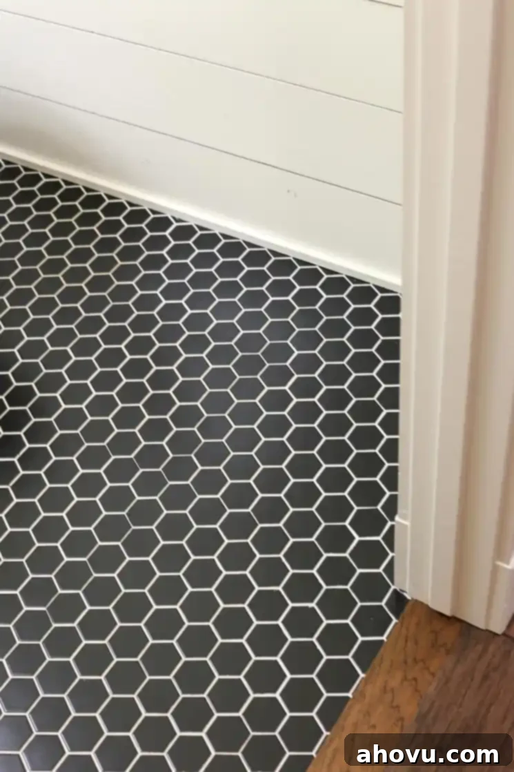 A stylish half bathroom floor with black hexagon tiles and contrasting white grout, perfectly complemented by shiplap walls.