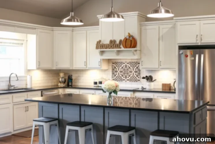 A beautifully designed modern farmhouse kitchen with white cabinets, black honed granite countertops, and a large gray island.