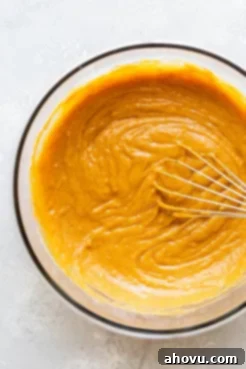 The perfectly mixed pumpkin bread batter, showing a smooth and slightly lumpy texture, ready for baking in a glass mixing bowl.