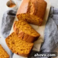 A freshly baked and sliced loaf of classic pumpkin bread on a marble serving tray.
