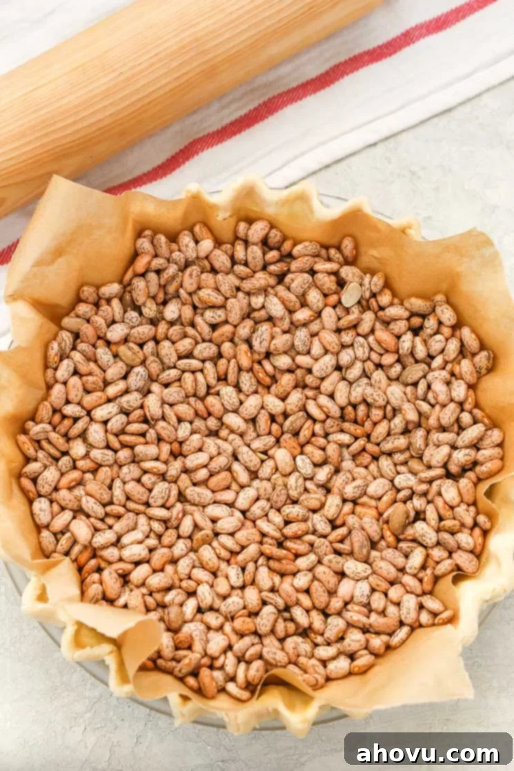A pie crust that's been topped with parchment paper and dried beans in preparation for blind baking. 