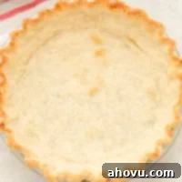 Overhead view of a blind baked pie crust next to a striped towel.