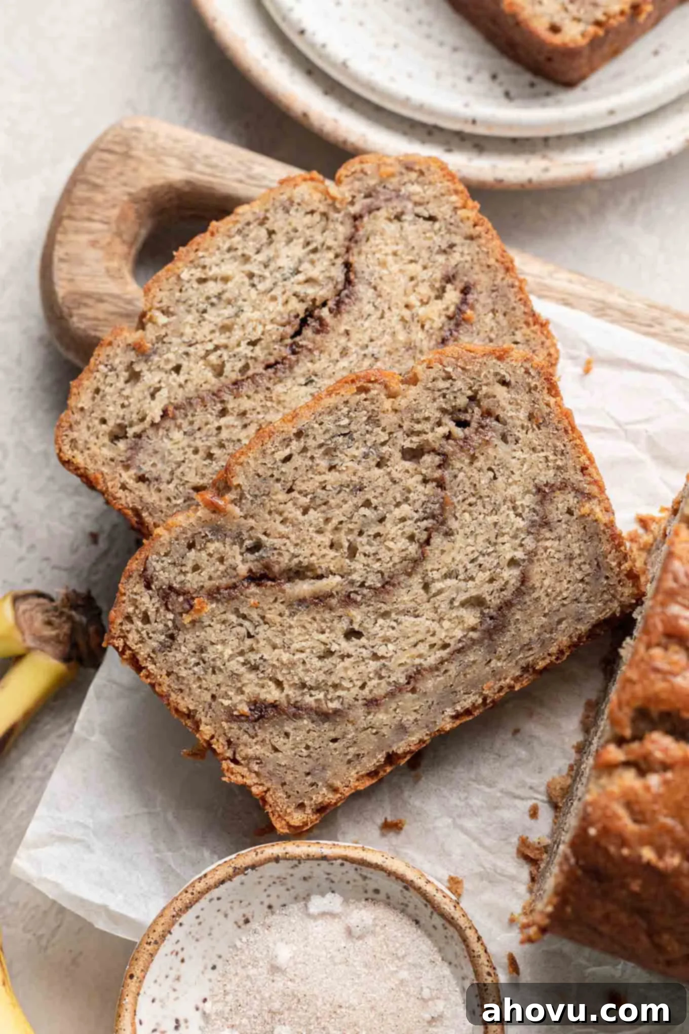 An overhead view of two slices of cinnamon swirl banana bread on a cutting board, showcasing the beautiful cinnamon ribbon.