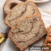 Two slices of cinnamon banana bread laying on a cutting board next to the rest of the loaf, ready to be enjoyed.