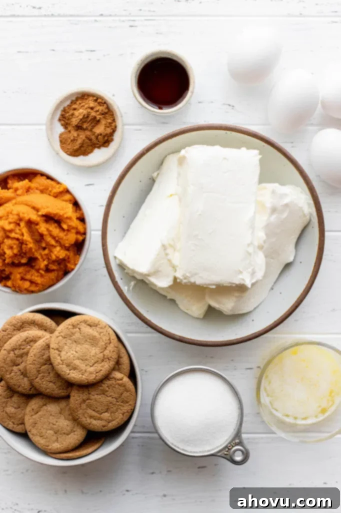 An overhead shot of various pumpkin cheesecake ingredients laid out neatly on a rustic white wood surface, ready for baking.