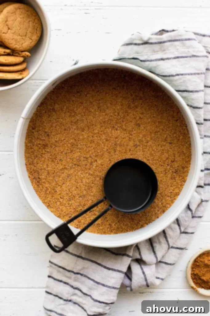 A close-up view of a springform pan with a perfectly pressed gingersnap cookie crust, ready for the filling.