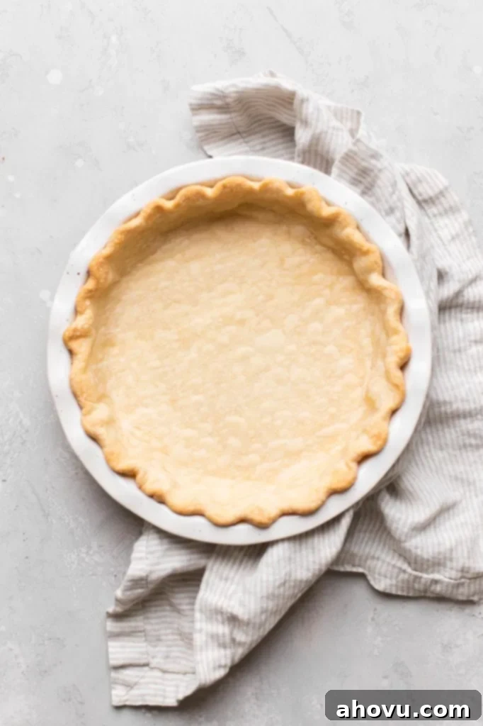 An overhead view of a perfectly blind-baked pie crust nestled in a white ceramic baking dish, ready for the delicious pecan filling.