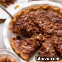 A whole classic pecan pie in a white ceramic baking dish, with several slices already cut, showcasing the rich filling and crunchy pecan topping.
