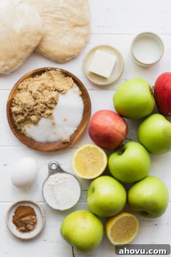 A collection of fresh apple pie ingredients, including sliced apples, spices, and dough, neatly arranged on a pristine white surface.
