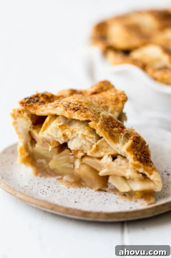 A mesmerizing close-up image of a single slice of apple pie, revealing the exquisite layers of its flaky golden crust and the tender, perfectly spiced apple filling within.