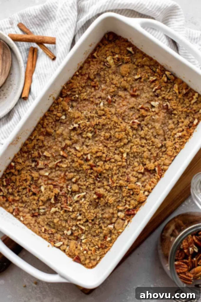 A beautifully baked sweet potato casserole, golden brown and topped with a generous pecan streusel, in a white baking dish.