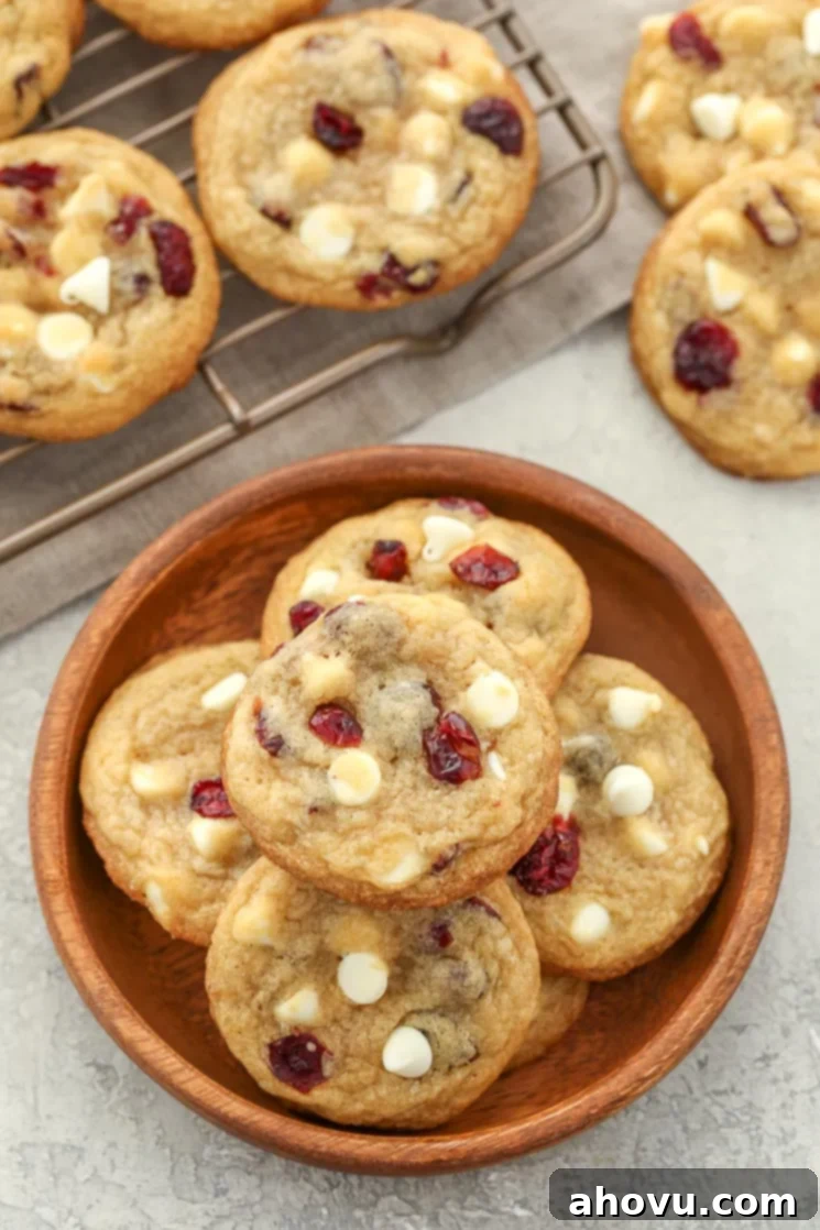 A close-up shot of raw white chocolate cranberry cookie dough balls on a parchment-lined baking sheet, ready for chilling and baking.