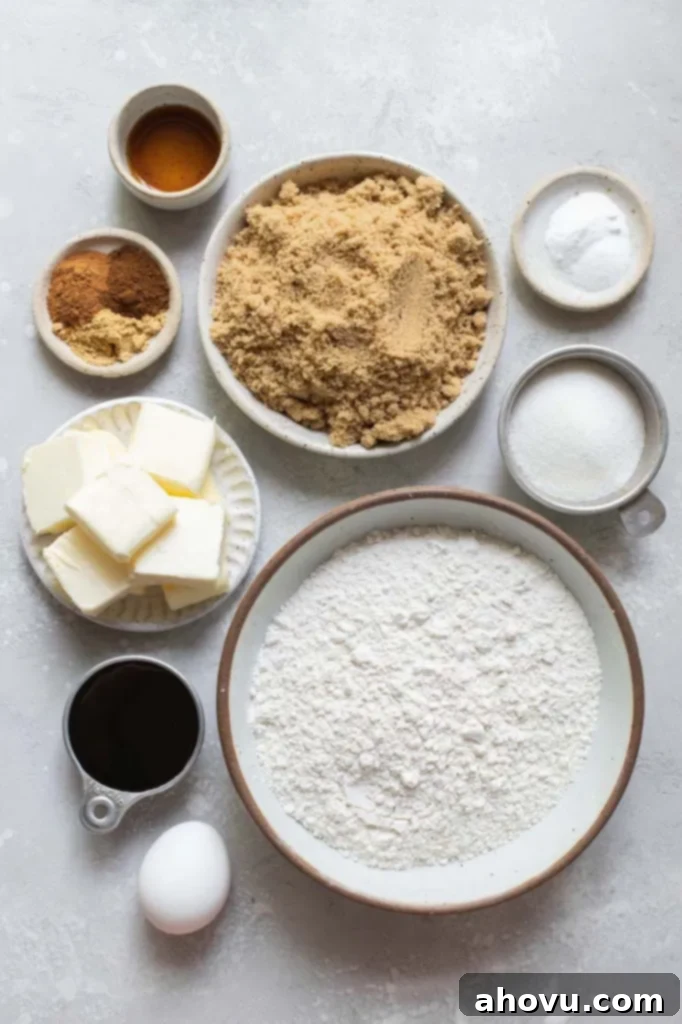 All the essential baking ingredients, including flour, sugar, molasses, butter, eggs, and various spices, thoughtfully arranged in small bowls on a rustic gray surface, ready for making delicious cookies.