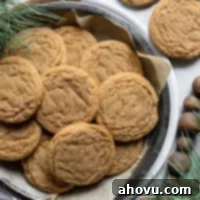 A baking pan lined with parchment paper and filled with perfectly baked soft molasses cookies, showcasing their inviting golden-brown color and cracked tops, ready to be cooled.