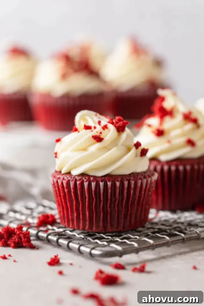 Velvety Red Delights 5 A beautiful side profile view of frosted red velvet cupcakes neatly arranged on a wire cooling rack, showcasing their fluffy texture and perfect frosting swirls.