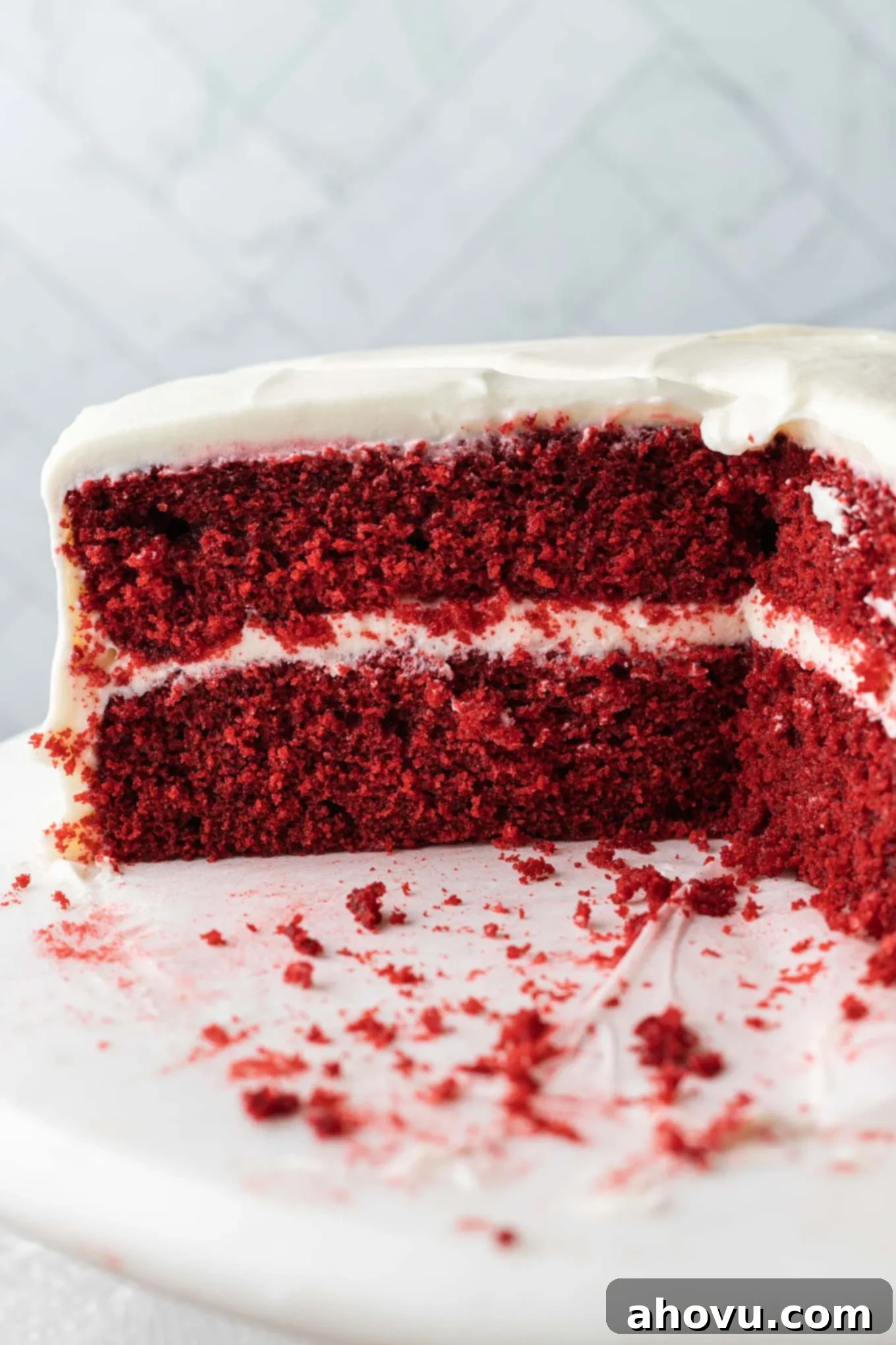 A side view of a sliced red velvet cake with cream cheese frosting. 