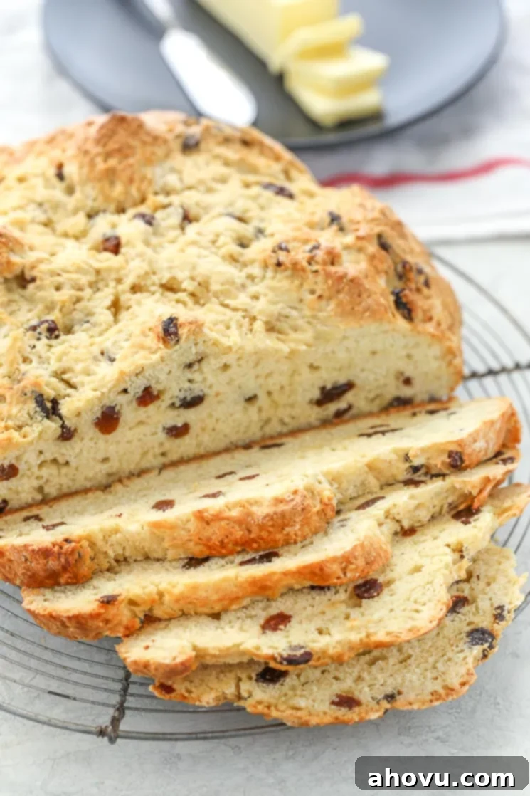 A sliced loaf of Irish Soda Bread on top of an antique round cooling rack with white and red napkin in the background. 