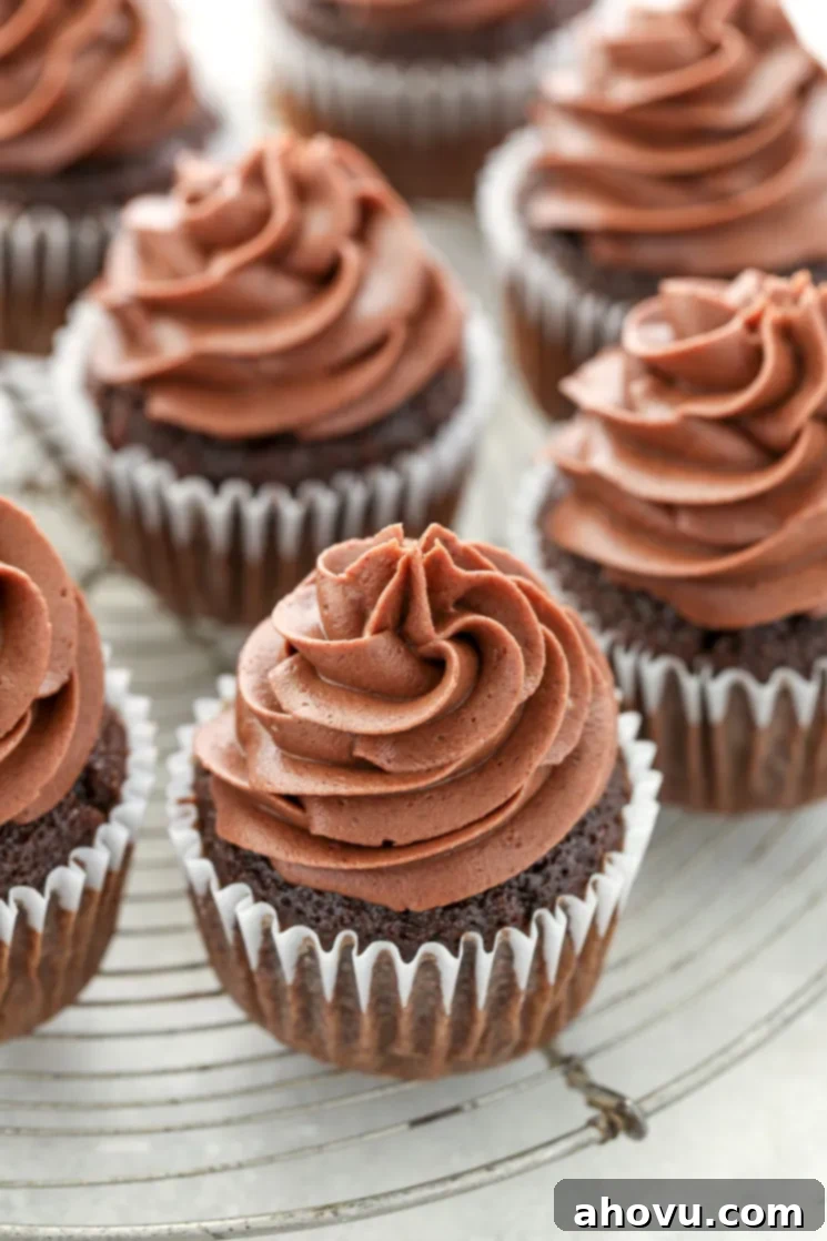 Velvet Chocolate Cream Cheese Bliss 2 A group of chocolate cupcakes topped with chocolate cream cheese frosting sitting on top of an antique round cooling rack.
