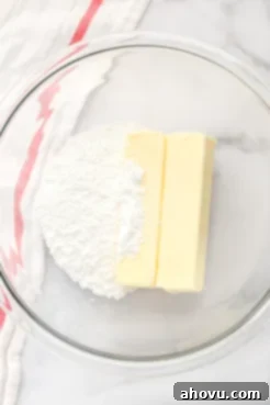 A glass bowl with two sticks of butter and powdered sugar.