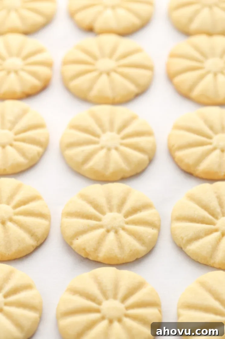 A baking sheet covered in parchment paper topped with shortbread cookies right out of the oven.