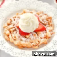 A funnel cake topped with strawberries and homemade whipped cream sitting on a decorative white plate.