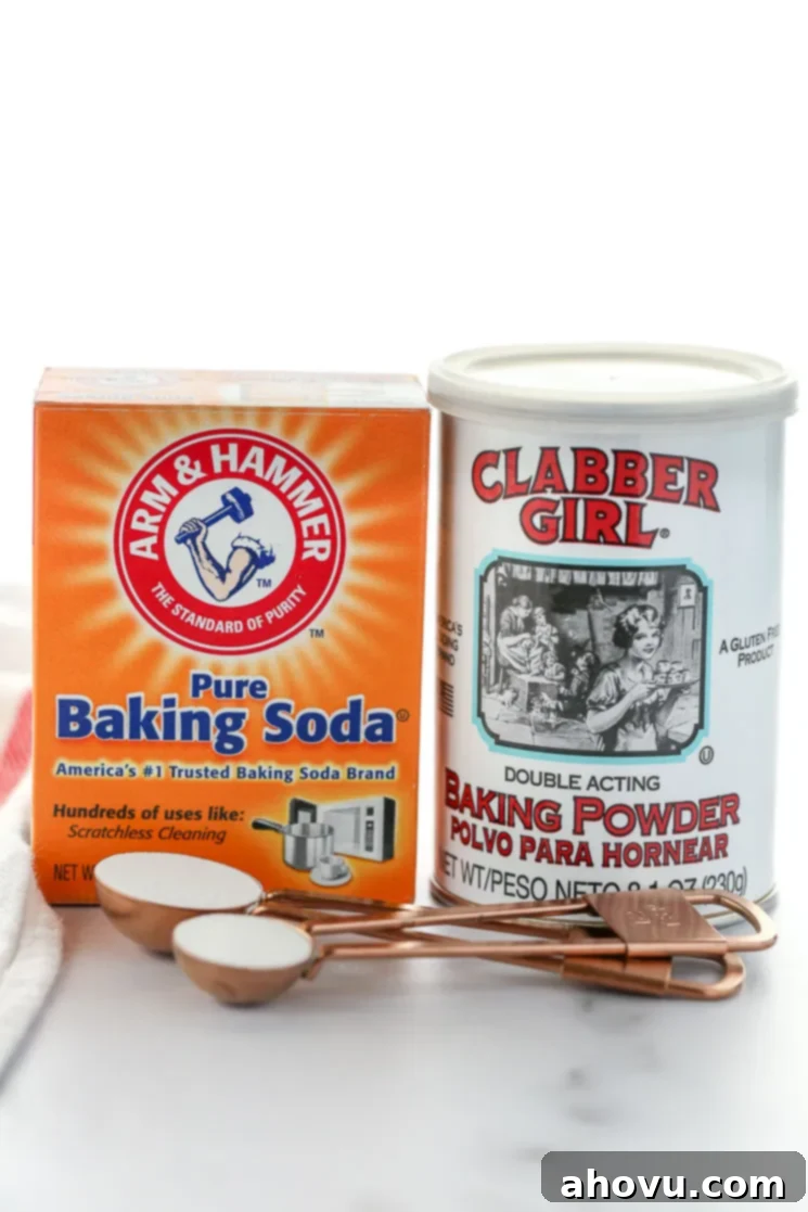 A box of baking soda and can of baking powder on top of a marble surface.