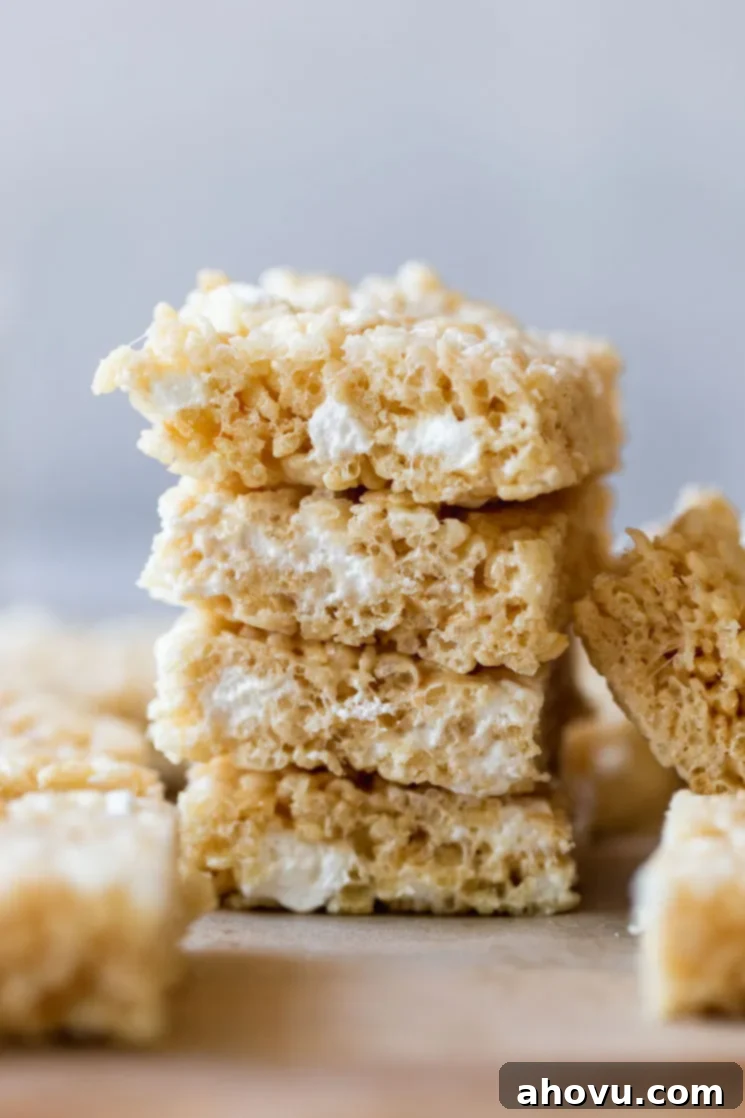 A stack of Rice Krispie treats on a wooden tray.