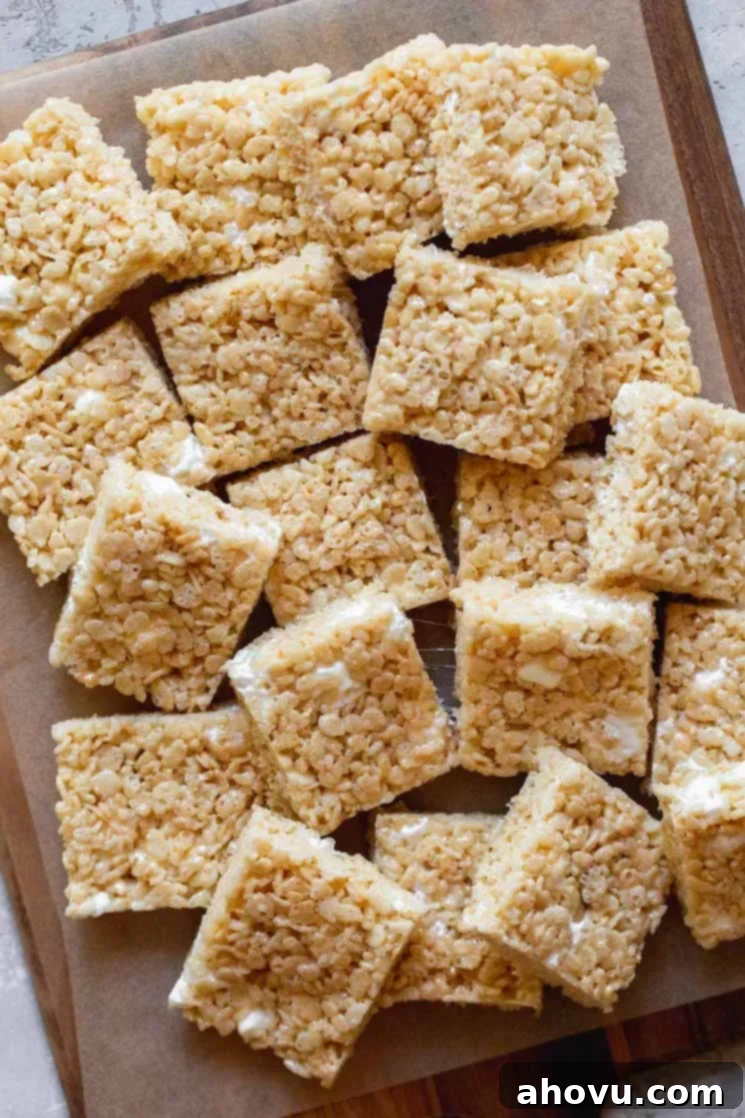 Multiple Rice Krispie treats squares arranged on a wooden tray.