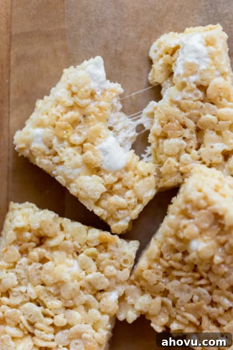 A close up image of a Rice Krispie treat being pulled apart with gooey marshmallow strings between the two halves.