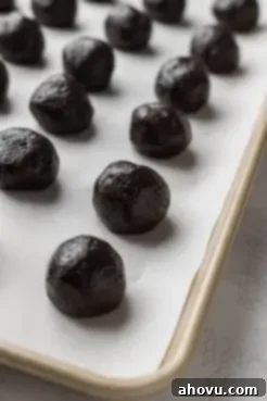 Rolled Oreo cream cheese balls on a parchment-lined baking sheet.