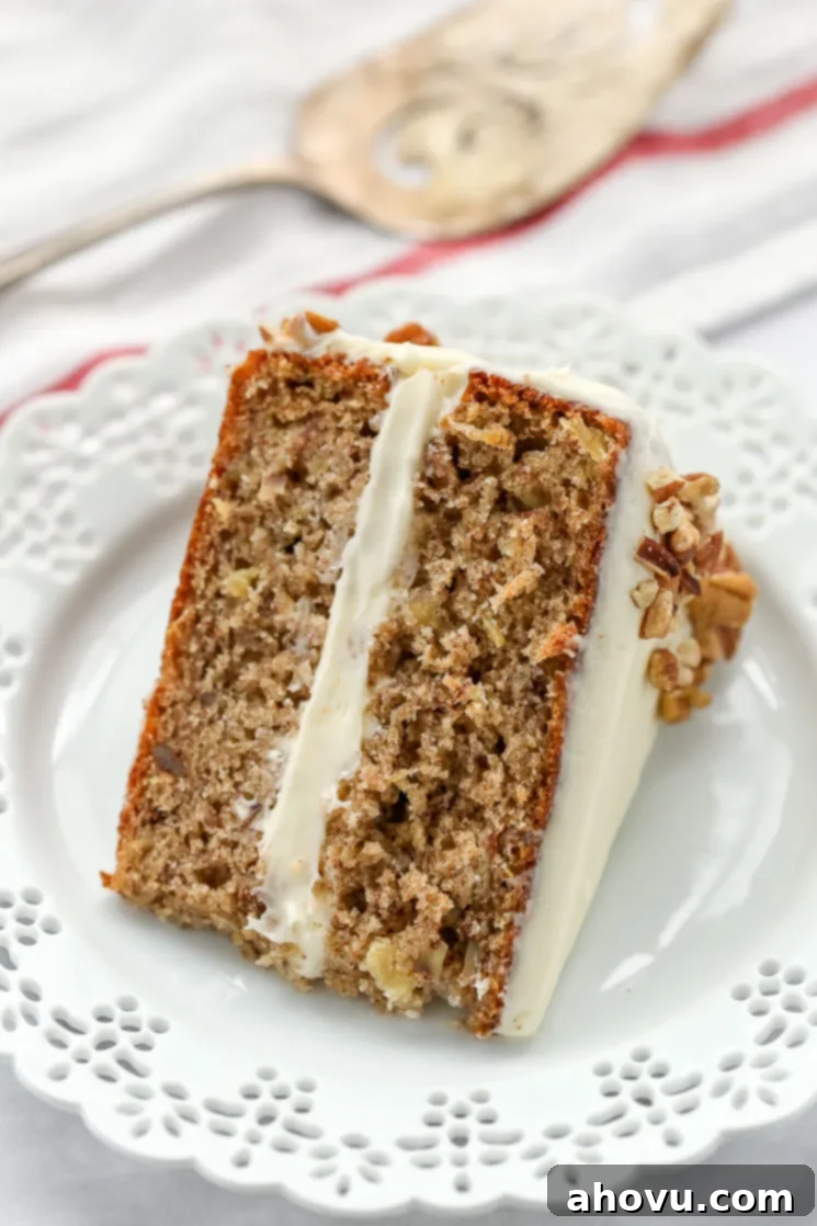 Sweet Nectar Cake 3 A freshly baked slice of classic hummingbird cake displayed on a decorative white plate, with a cake server ready to serve another piece, showcasing its perfectly layered structure.