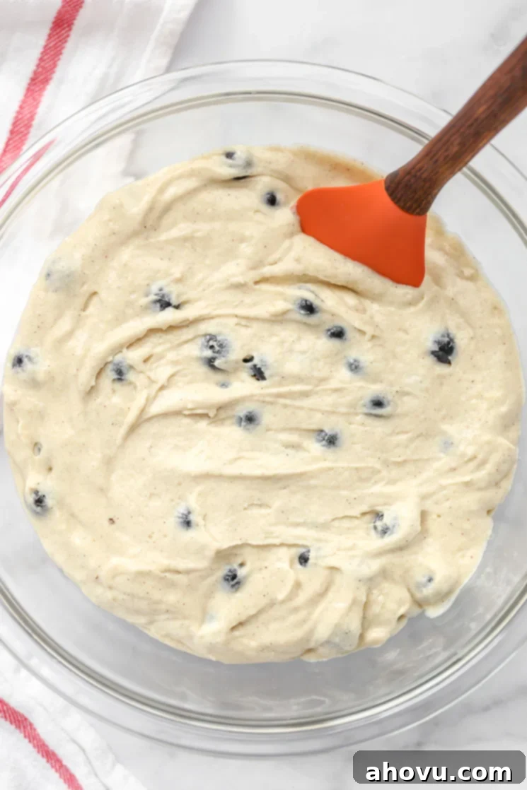A glass bowl filled with blueberry muffin batter.