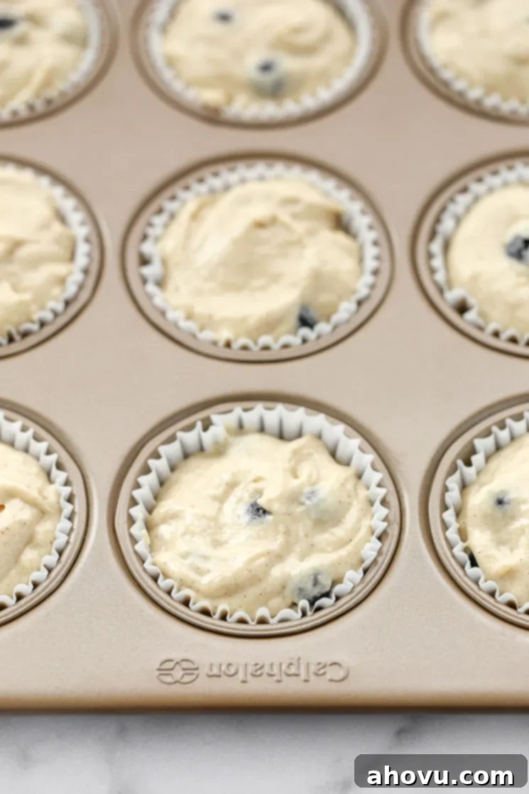 A muffin pan lined with cupcake liners and filled with the muffin batter.