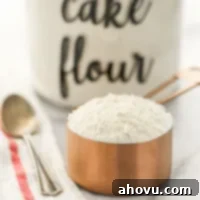 A close-up picture of a copper measuring cup filled with cake flour.