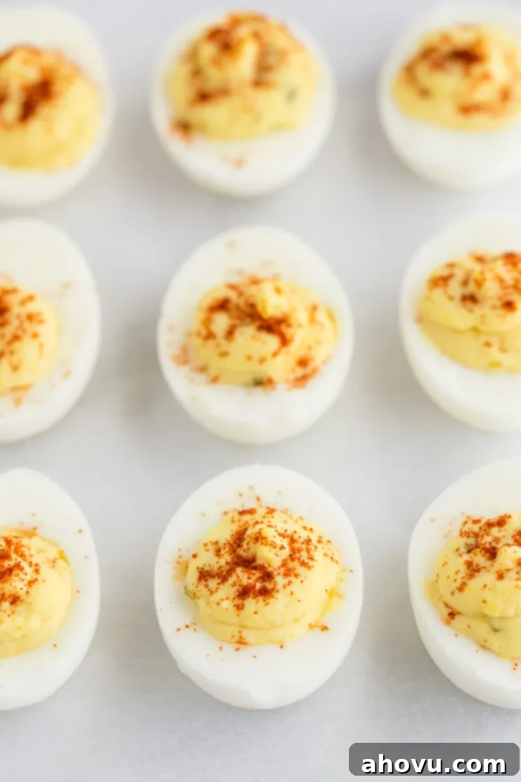 Spiced Yolk Delights 5 Freshly made deviled eggs neatly lined up on a piece of parchment paper, ready for chilling or serving.