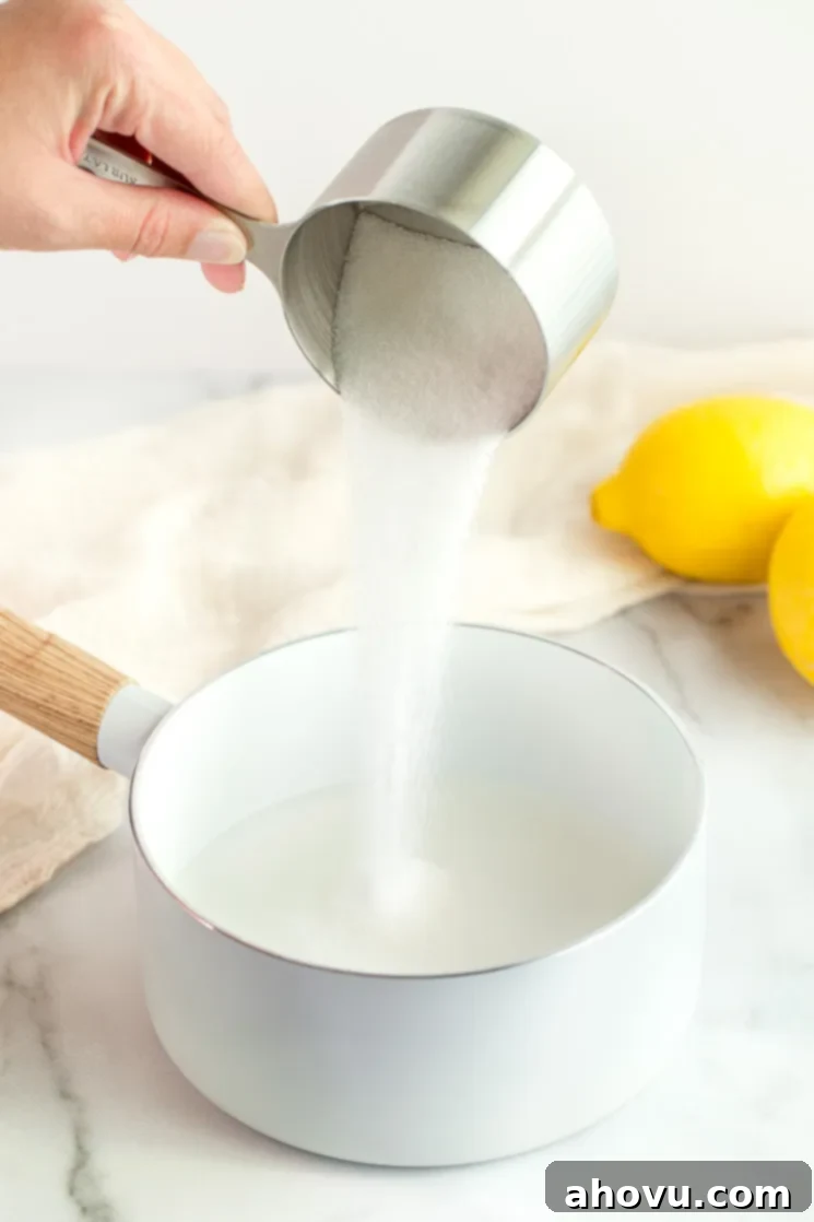 A hand adding a cup of sugar to a saucepan filled with water.